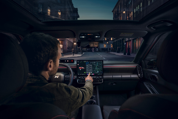Man using touchscreen in a car's dashboard, displaying a map for navigation.