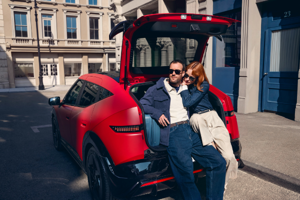 Couple sitting in the boot of a red SUV with the tailgate open.