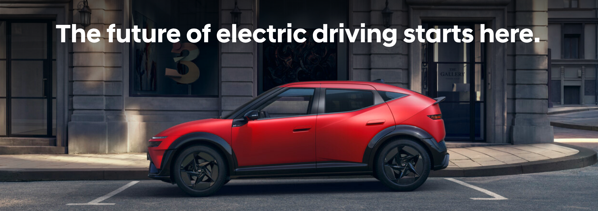 A red electric car parked on a city street with text above it.